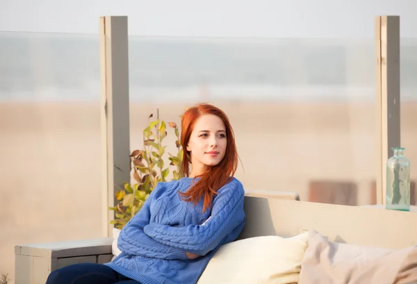 Рыжая девушка, сидящая в кафе возле морского побережья . — стоковое фото