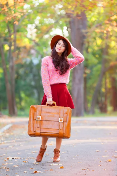 Piękna brunetka dziewczynka z walizka w parku. — Zdjęcie stockowe