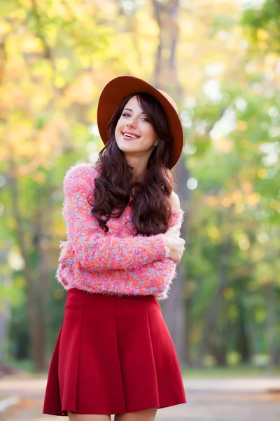 Menina morena em suéter rosa no parque de outono . — Fotografia de Stock