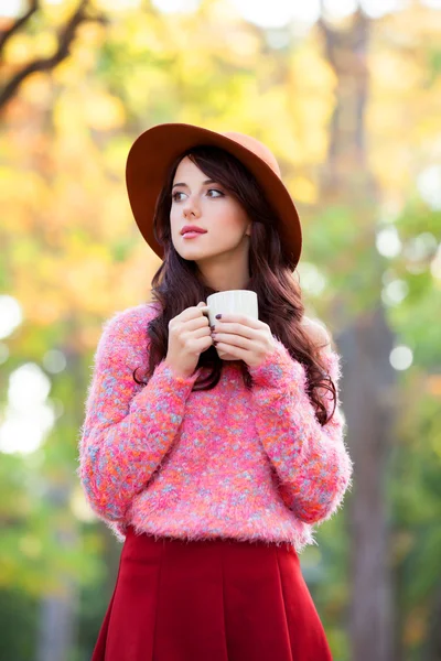 Brunetka dziewczynka z filiżanką kawy w parku jesień. — Zdjęcie stockowe