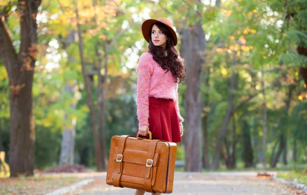 Mooie brunette meisje met koffer in het park. — Stockfoto