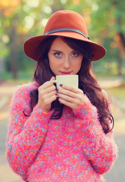 Bruneta fata wtih ceasca de cafea în the toamna parc . — Fotografie, imagine de stoc