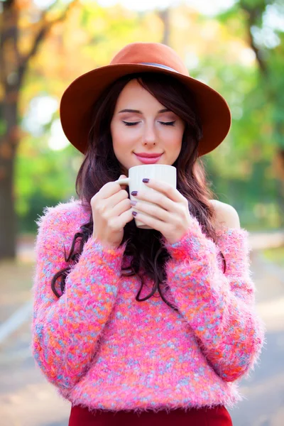 秋の公園でコーヒーのカップとブルネットの少女. — ストック写真