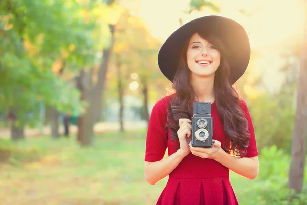 Brunette girl with camera in the park in sunset time — Stock Photo, Image