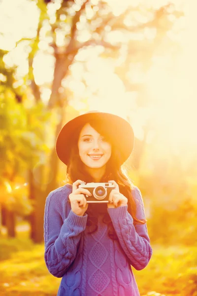 สาวผมสีบรูเนทกับกล้องในสวนในเวลาพระอาทิตย์ตก — ภาพถ่ายสต็อก