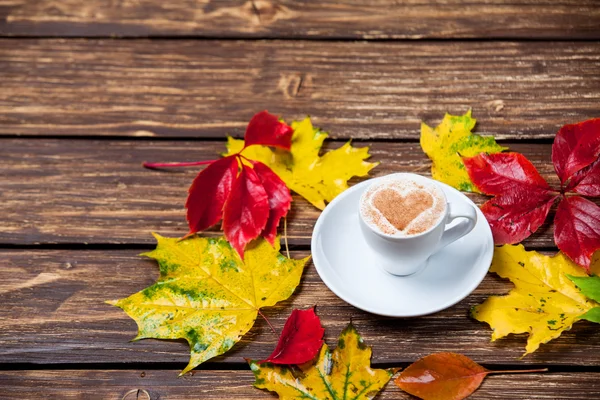 Sonbahar yaprakları ve ahşap masa fincan kahve. — Stok fotoğraf