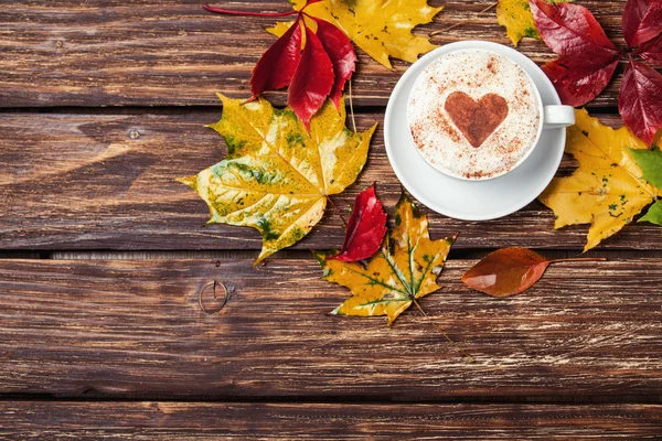 Herfst bladeren en koffie cup op houten tafel. — Stockfoto