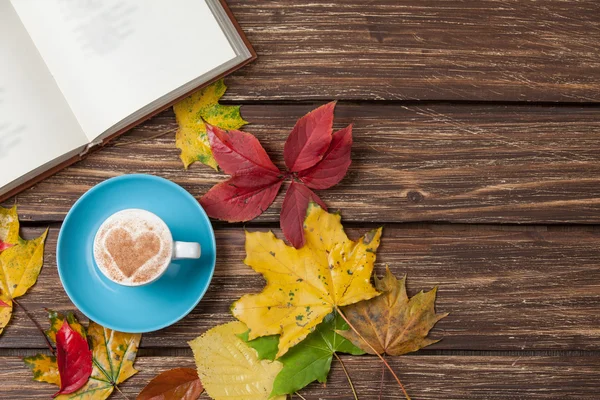 Herfst bladeren, boek en koffie cup op houten tafel. — Stockfoto