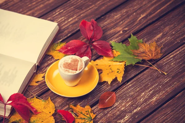 Herfst bladeren, boek en koffie cup op houten tafel. — Stockfoto