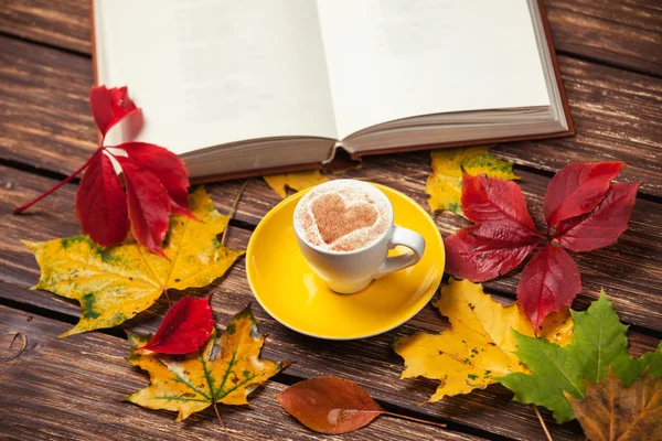 Feuilles d'automne, livre et tasse à café sur table en bois . — Photo