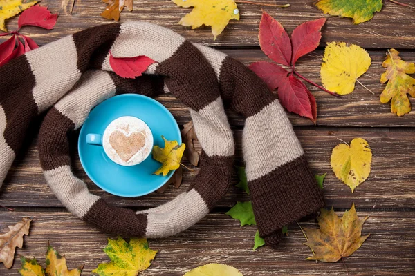 Autumn leafs, scarf and coffee cup on wooden table. — Stock Photo, Image