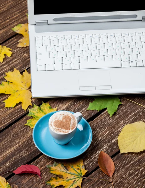 Осінні листочки, блокнот і чашка кави на дерев'яному столі . — стокове фото