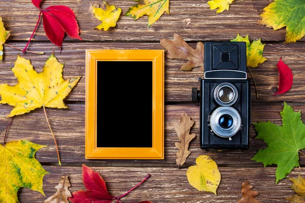 Autumn leafs, camera and frame on wooden table. — Stock Photo, Image