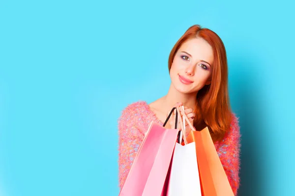 Fille rousse avec des sacs à provisions sur fond bleu . — Photo