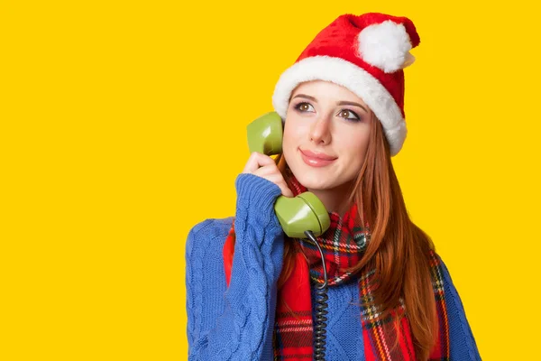 Menina ruiva bonita em chapéu de Natal com telefone em amarelo — Fotografia de Stock