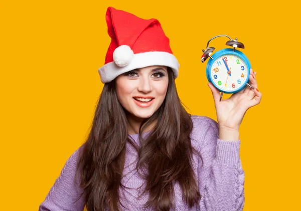 Brunette girl with alarm clock on yellow background. — Stock Photo, Image