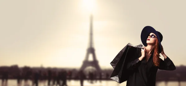巴黎的背景上的购物袋的红发女性. 图库图片