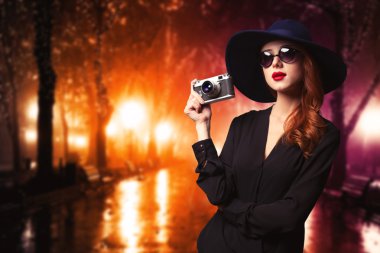 Kızıl saçlı kadın güneş gözlüğü ve vintage fotoğraf makinesi ile stil.