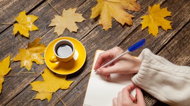 Bir şey kahve yakınındaki Not defterinizdeki yazma el.