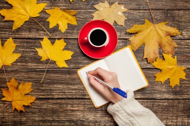 Bir şey kahve yakınındaki Not defterinizdeki yazma el.