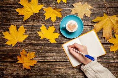 Bir şey kahve yakınındaki Not defterinizdeki yazma el.