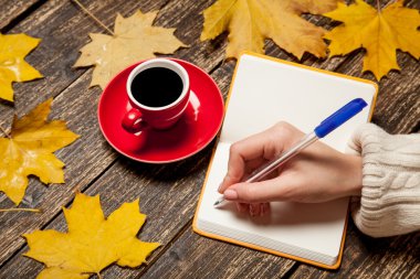 Bir şey kahve yakınındaki Not defterinizdeki yazma el.