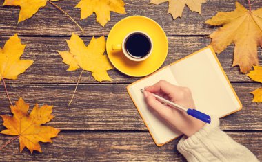 Bir şey kahve yakınındaki Not defterinizdeki yazma el.