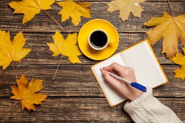 Bir şey kahve yakınındaki Not defterinizdeki yazma el.