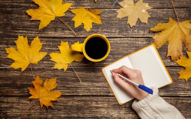 Bir şey kahve yakınındaki Not defterinizdeki yazma el.