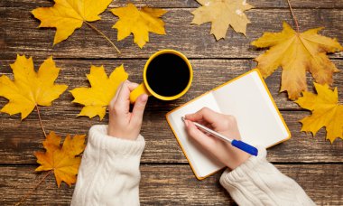 Bir şey kahve yakınındaki Not defterinizdeki yazma el.