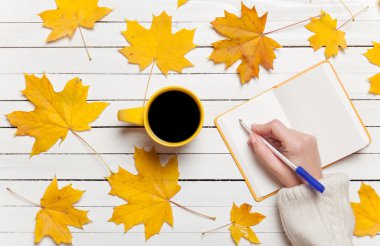 Bir şey kahve yakınındaki Not defterinizdeki yazma el.