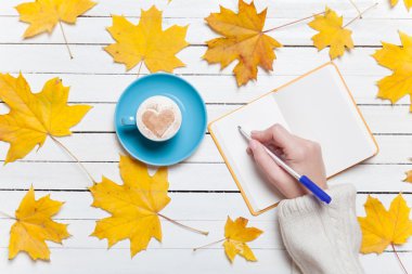 Bir şey kahve yakınındaki Not defterinizdeki yazma el.