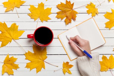 Bir şey kahve yakınındaki Not defterinizdeki yazma el.