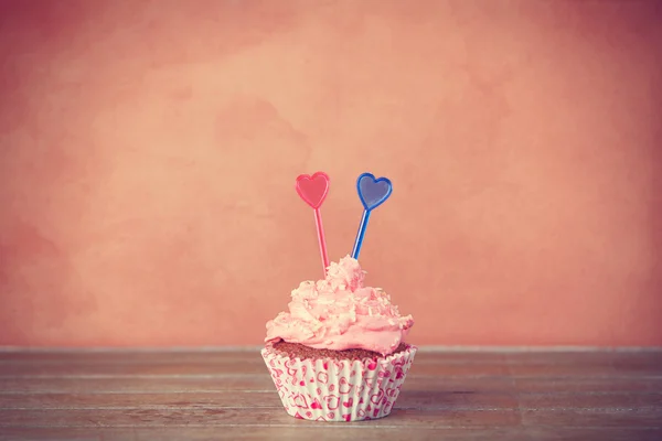 Cupcake com nata rosa em uma mesa . — Fotografia de Stock