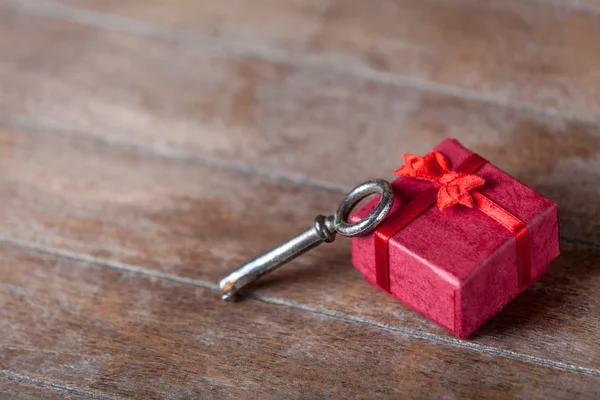 Chave retrô e pequeno presente vermelho na mesa de madeira . — Fotografia de Stock