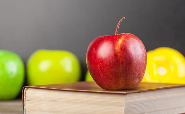 Rött äpple och bok på ett bord. — Stockfoto