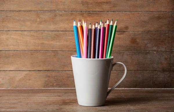 彩色铅笔在杯上一个木制的背景 — 图库照片