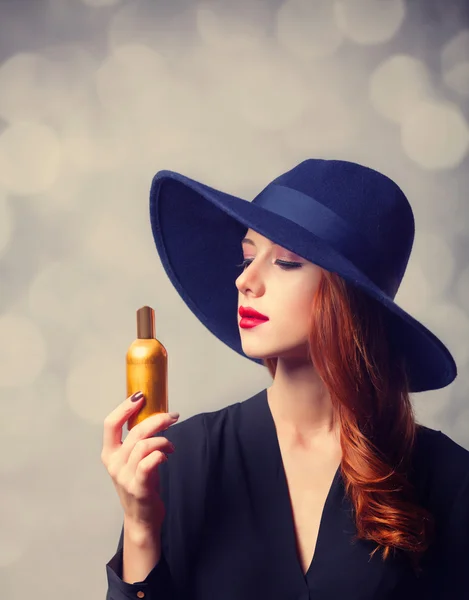 Rödhårig tjej i en hatt hålla parfym — Stockfoto