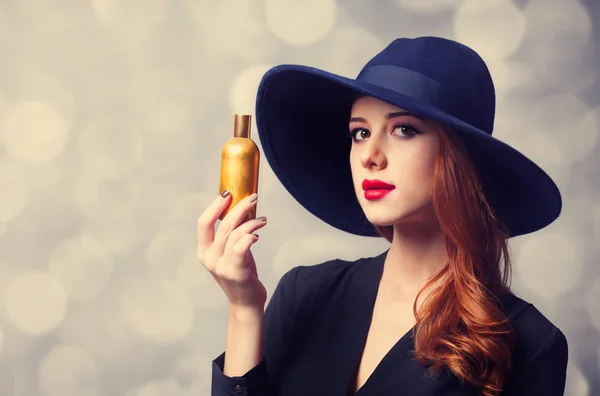 Style redhead girl in a hat holding perfume — Stock Photo, Image