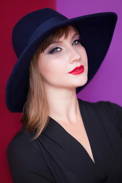 Menina morena com chapéu no fundo vermelho e violeta . — Fotografia de Stock