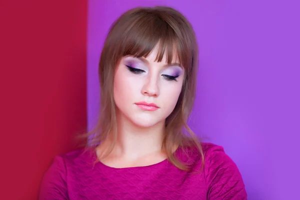Traurige Brünette Mädchen auf violettem und rotem Hintergrund. — Stockfoto