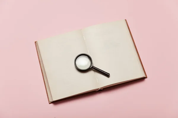 Opened book and loupe on color background. — Stock Photo, Image