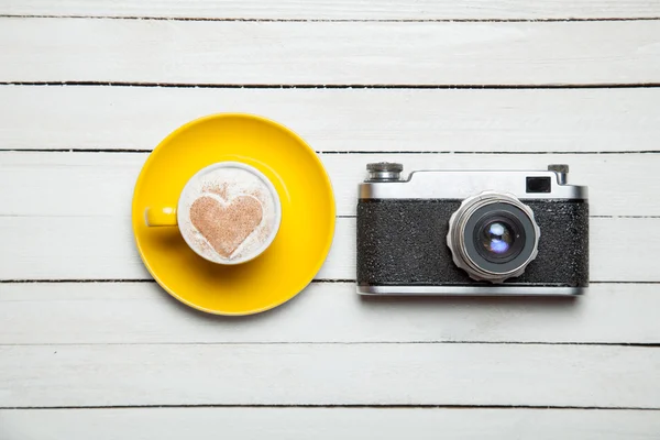Retro camera and cup of coffee on wooden table. — Stock Photo, Image