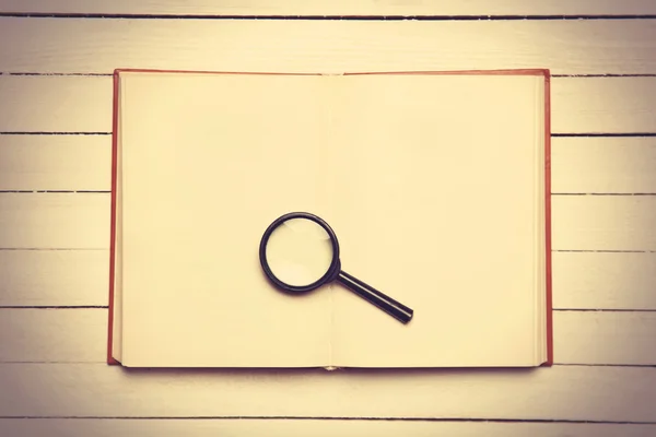Opened book and loupe on it. — Stock Photo, Image