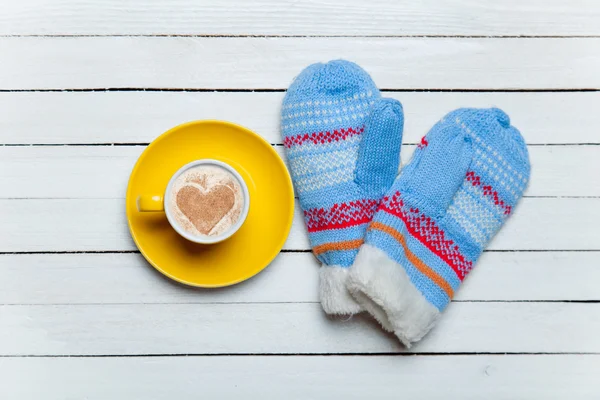 Coffee with heart shape symbol and mittens on wooden table. — Stock Photo, Image