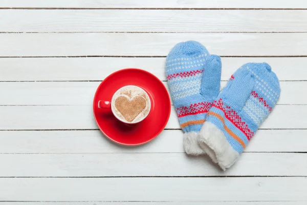 Coffee with heart shape symbol and mittens on wooden table. — Stock Photo, Image
