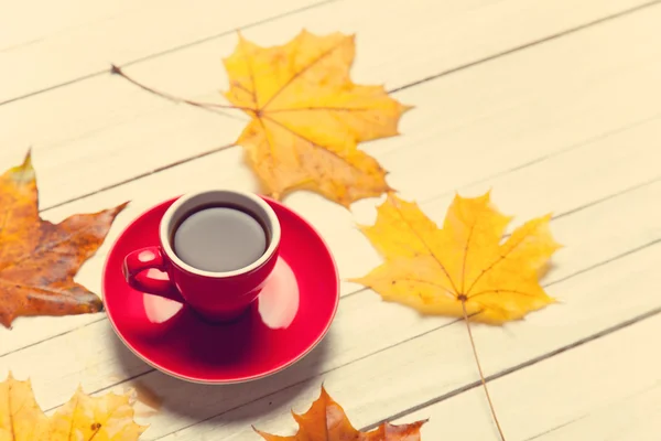 Cup of coffee and leafs on wooden table. — Stock Photo, Image