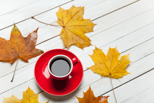 Kahve ve ahşap masa üzerinde yapraklar. — Stok fotoğraf