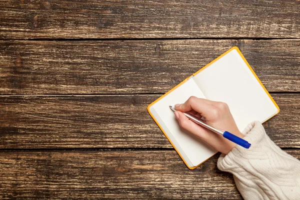 Vrouwelijke hand schrijven iets in om op te merken — Stockfoto