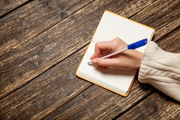 Female hand writing something in to note — Stock Photo, Image